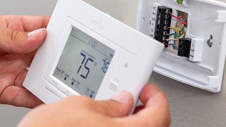 person installing smart thermometer