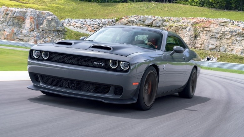 2019 Dodge Challenger SRT Hellcat driving around a turn with a rocky outcrop in the background