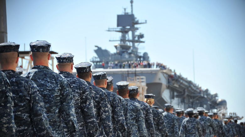 U.S. sailors and marines line up to board a U.S. amphibious assault ship.