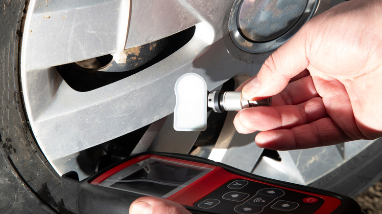 Hand installing TPMS sensor to tire
