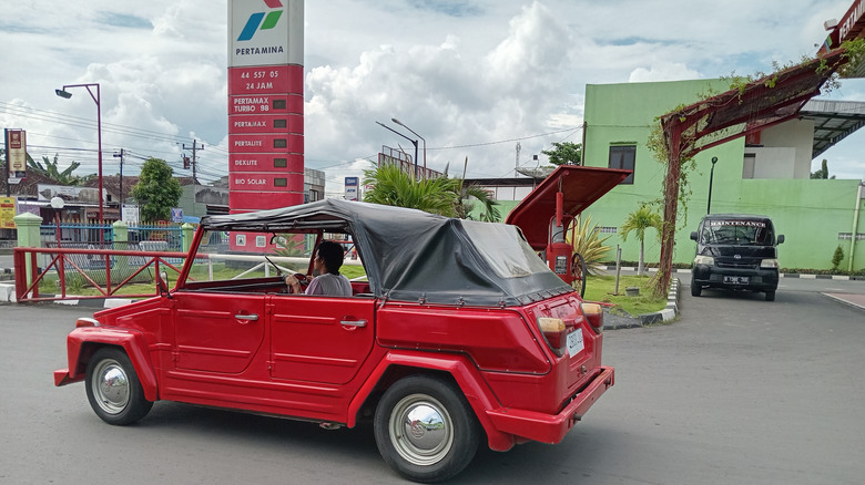 red classic volkswagen car parked in the gas station area after filling up with fuel