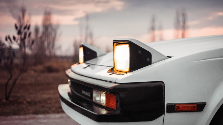 1980s Toyota Supra with pop-up headlights deployed, left-side close-up view