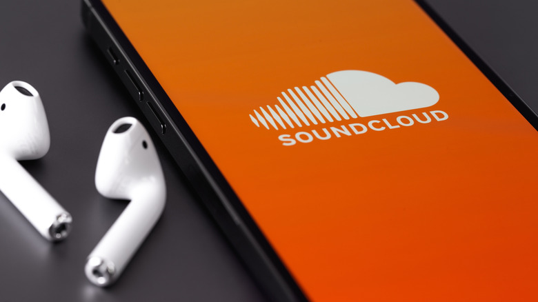 iPhone with SoundCloud splash screen next to AirPods