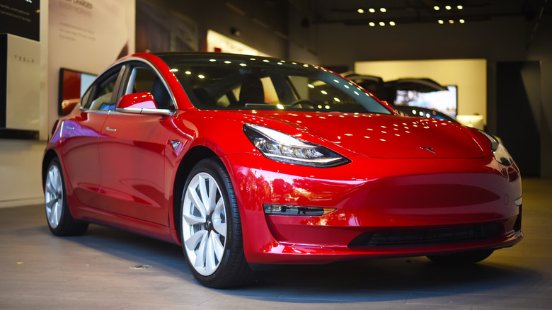 Red Tesla Model 3 displayed inside a showroom